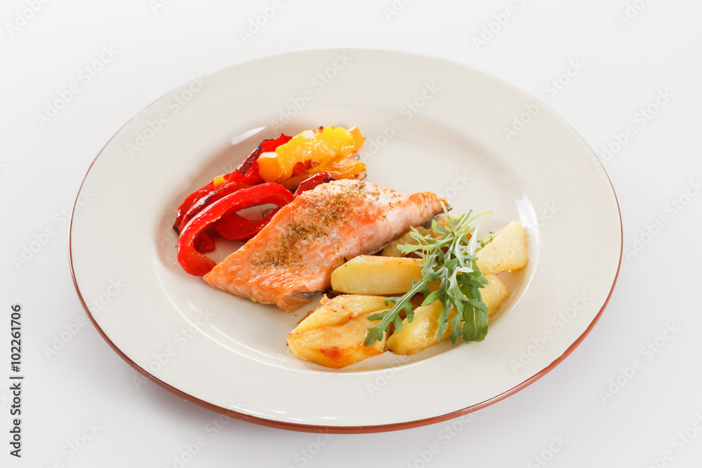 Grilled salmon fillet with vegetables, spices and arugula on a plate Grilled salmon fillet with vegetables, spices and arugula on a plate