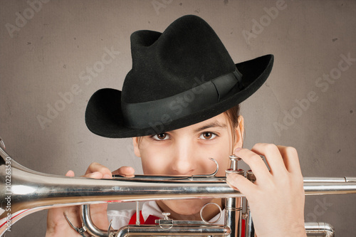 little girl playing trumpet on a gray background