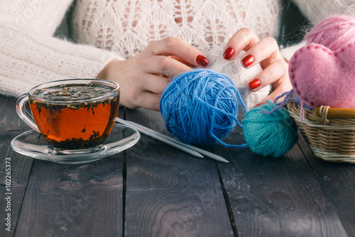 Beautiful girl in a white dress hand knitting with a cup of tea