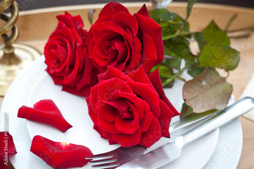 Table setting with red roses on plate - celebrating Valentine s