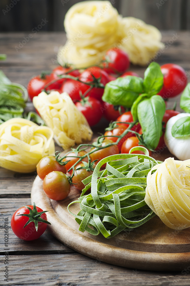 Raw pasta, tomato and basil on the wooden table Raw pasta, tomato and basil on the wooden table