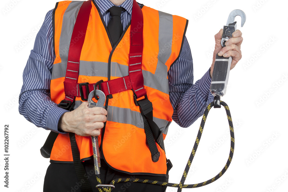 Building Surveyor in orange visibility vest securing safety harn Building Surveyor in orange visibility vest securing safety harn