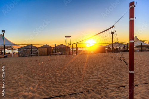 Sillhouette of a volleyball net and sunrise on the beach