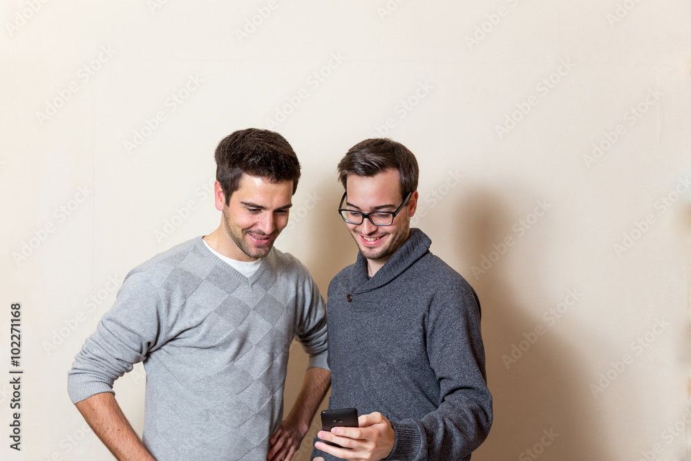 Zwei Männer schauen lächelnd auf ein Smartphone Zwei Männer schauen lächelnd auf ein Smartphone