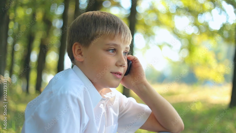 child teen boy talking on mobile phone outdoor, uses a touchscreen gadget smartphone. child teen boy talking on mobile phone outdoor, uses a touchscreen gadget smartphone.