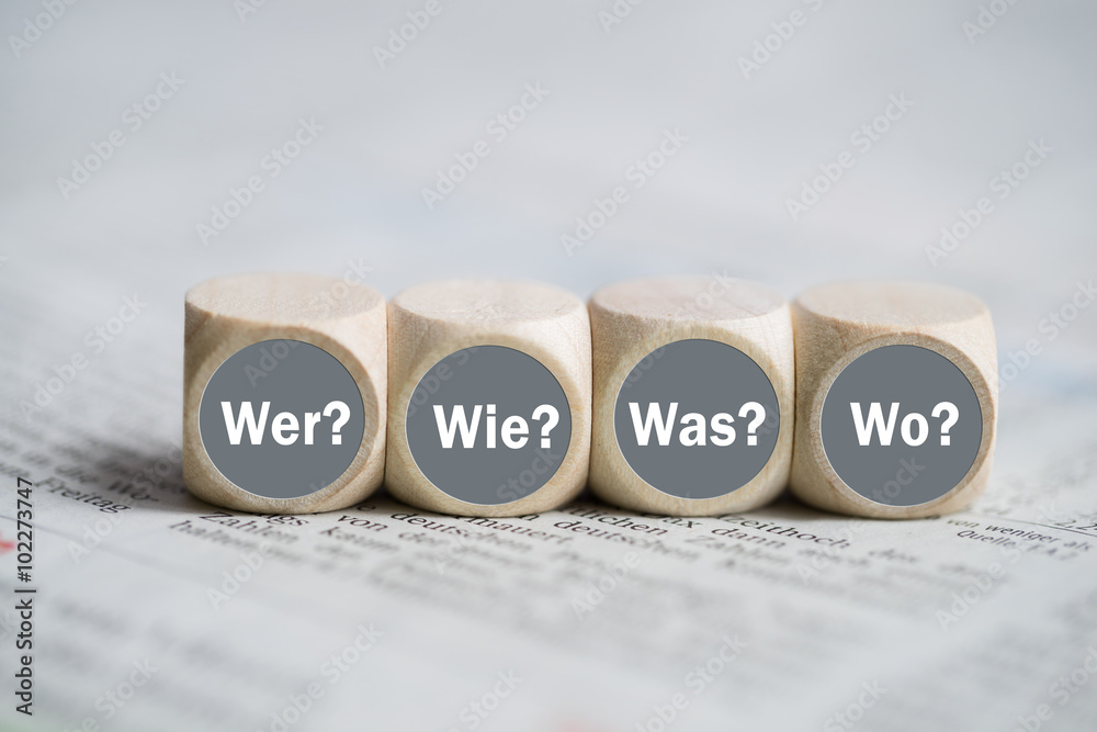 Würfel mit den Wörtern "Wer, Wie, Was und Wo" auf einer Zeitung - obrazy, fototapety, plakaty 