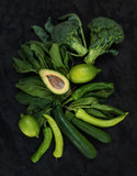 Raw green vegetables set. Broccoli, avocado, pepper, spinach, zuccini, lime on  dark stone background