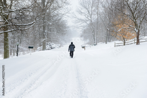 Lone Man Walking Down Street During Snowstorm