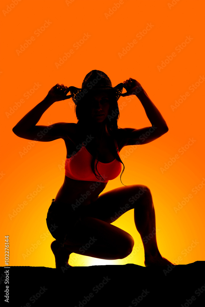 Silhouette of cowgirl low hands on hat Silhouette of cowgirl low hands on hat