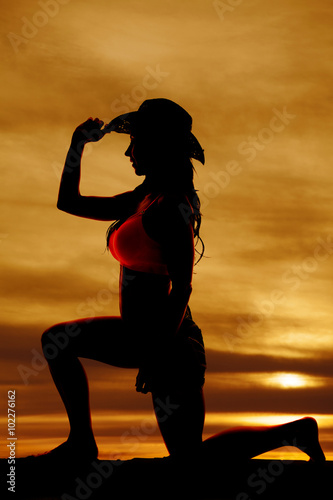 Silhouette of cowgirl side on one knee