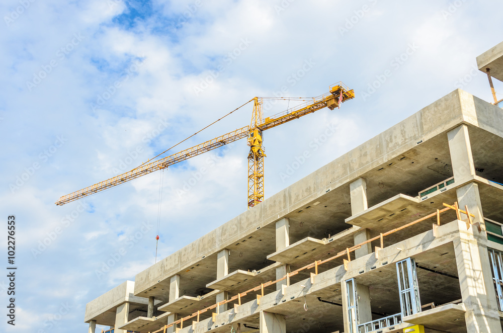 High-rise building under construction. The site with cranes against blue sky High-rise building under construction. The site with cranes against blue sky