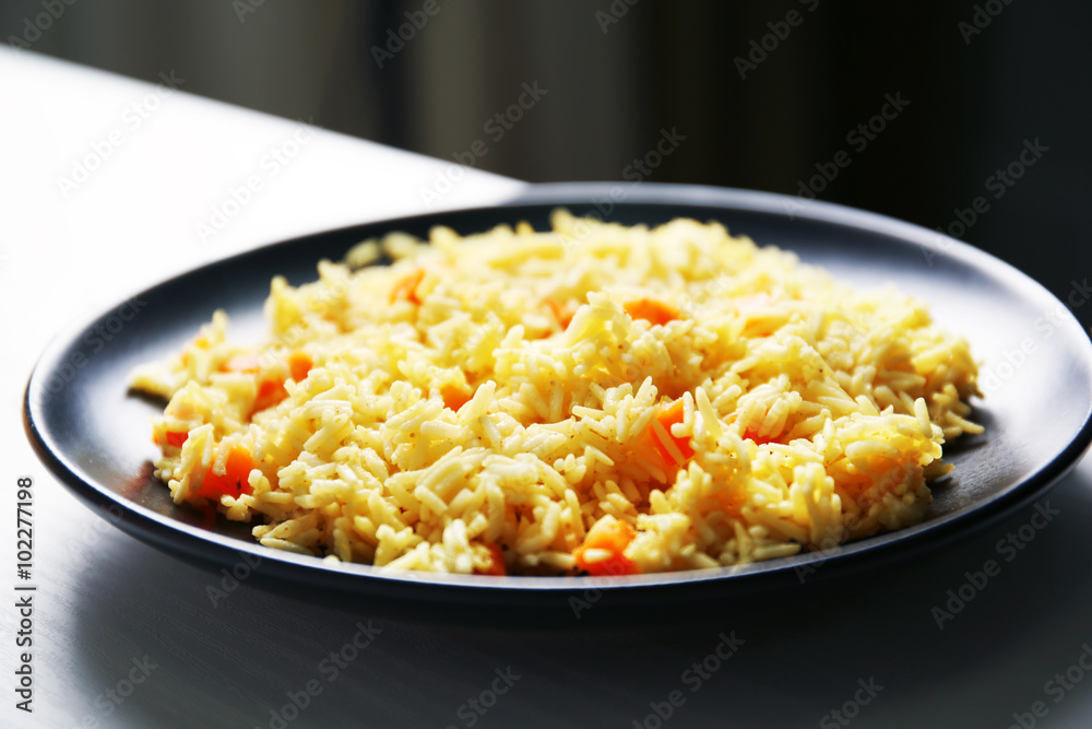 Stewed rice with a carrot on a black plate, close up Stewed rice with a carrot on a black plate, close up