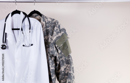 Obraz na plátně Medical white consultation coat and military uniform on hanger