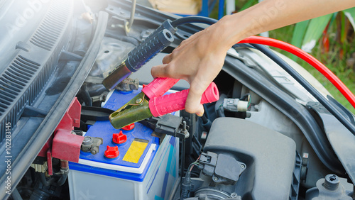 Hand holding jumper cable for recharge the battery car