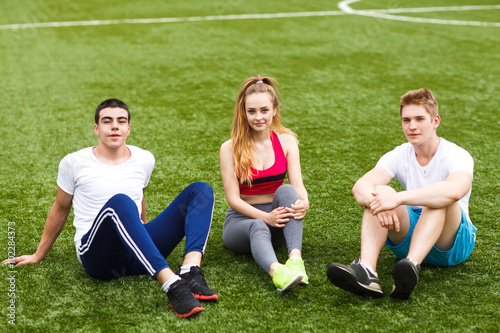 young sport people sitting on the grass