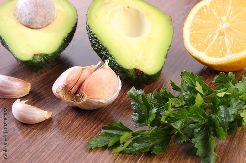 Avocado, garlic, lemon and parsley on wooden background, ingredient of avocado paste or guacamole, healthy food and nutrition