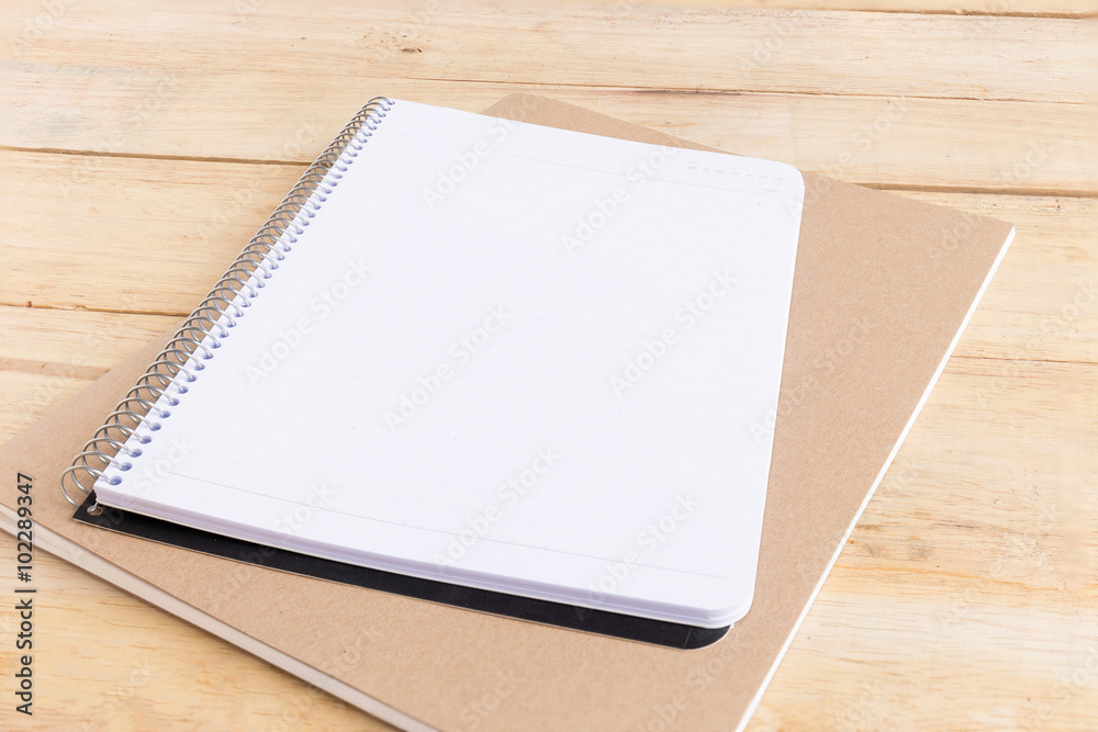 Blank white notebook with pen on wood desk. shallow depth of field