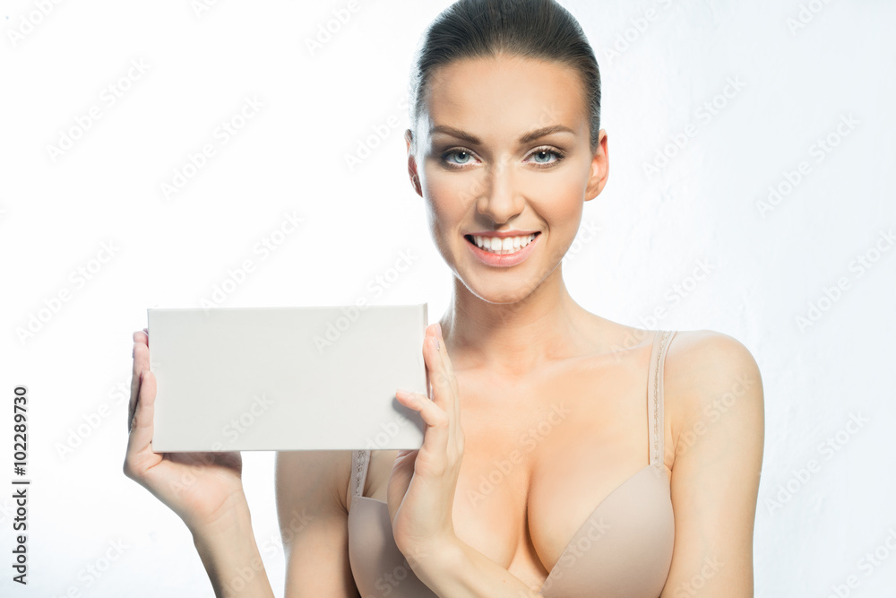 Woman with natural make-up shows the blank form for writing and smiling Woman with natural make-up shows the blank form for writing and smiling