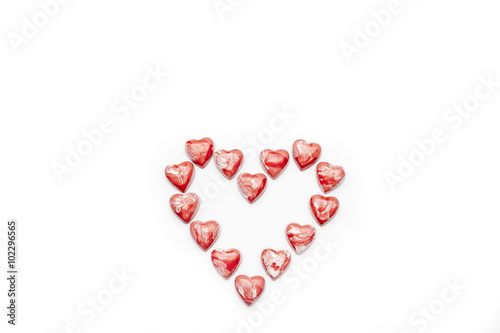 Red and white heart shaped chocolates arranged in heart on white background directly from above copy space