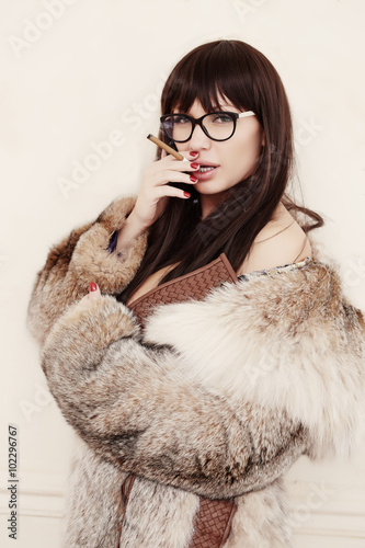 Brunette woman in eyeglasses and in a fur coat.