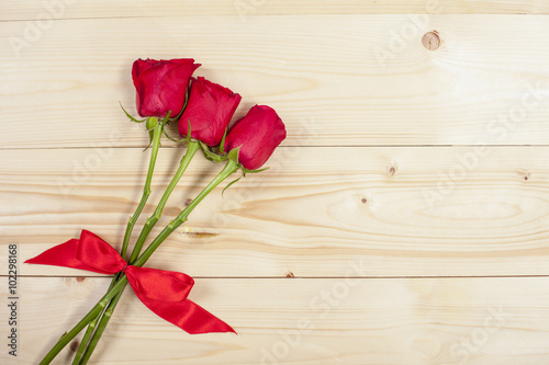Three red roses on a wooden board