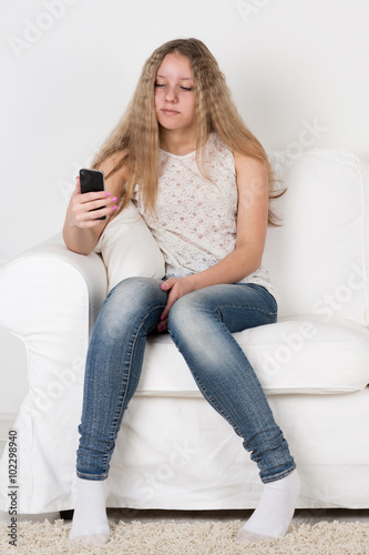 Teen girl sitting on the couch and looking at the phone