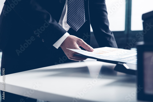 Businessman analyzing investment charts with printer. Accounting