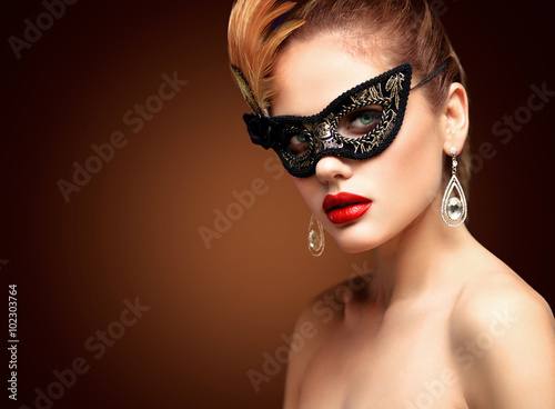 Beauty model woman wearing venetian masquerade carnival mask at party isolated on black background. Christmas and New Year celebration. Glamour lady with perfect make up and hairstyle