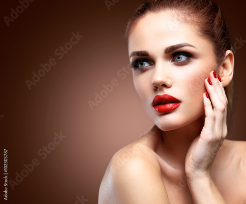 Beauty Model Woman with Long Brown Wavy Hair. Healthy Hair and Beautiful Professional Makeup. Red Lips and Smoky Eyes Make up. Gorgeous Glamour Lady Portrait. Haircare  Skincare concept