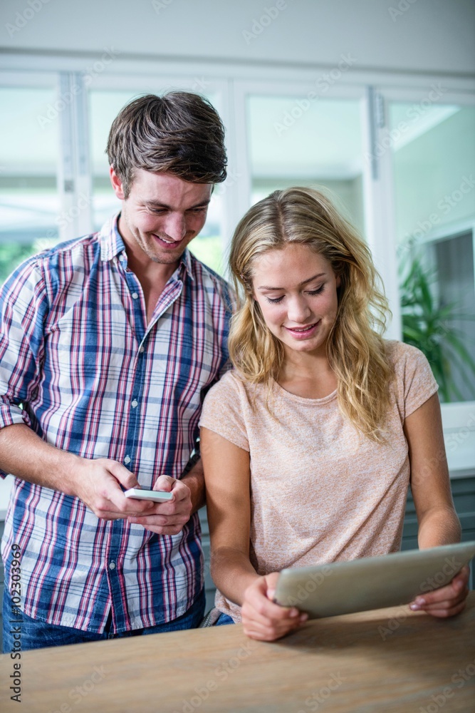 Cute couple using tablet computer in the kitchen Cute couple using tablet computer in the kitchen