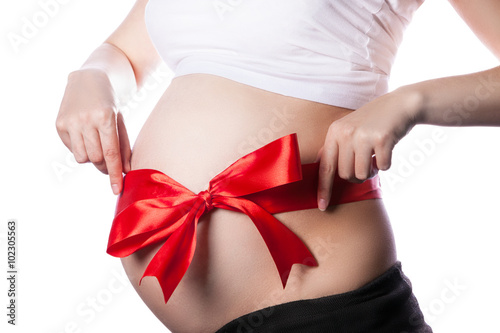 Pregnant Woman Belly with Red Ribbon and Big Bow. Expecting Baby Pregnancy Concept