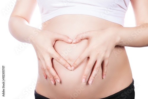 Pregnant Woman holding her hands in a heart shape on her baby bump. Pregnant Belly with fingers Heart symbol. Maternity concept. © akvafoto2012