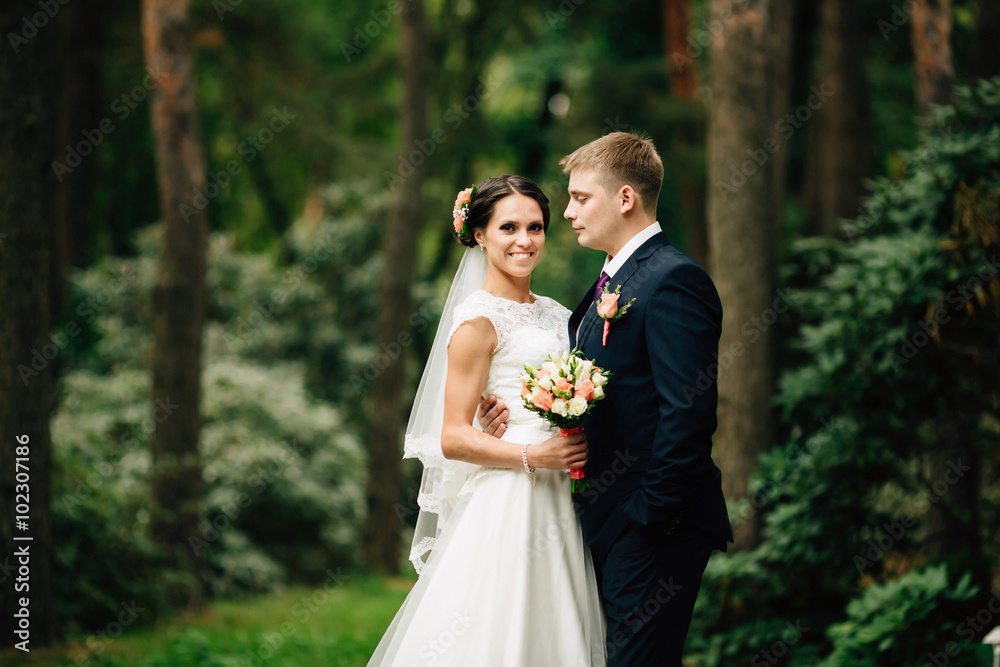 Beautiful bride and groom walking outdoors in park. Beautiful bride and groom walking outdoors in park.