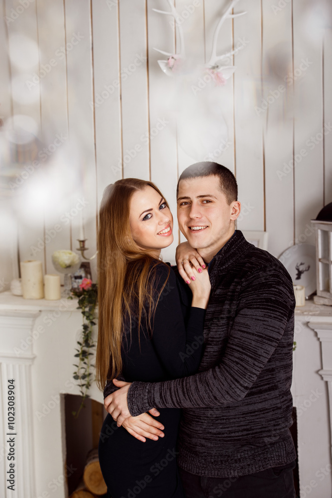 Portrait of young loving couple embracing indoors at fireplace Portrait of young loving couple embracing indoors at fireplace
