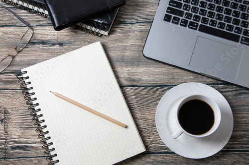 Working desk with coffee laptop glasses book notepad supplies and tablet  on wooden desk