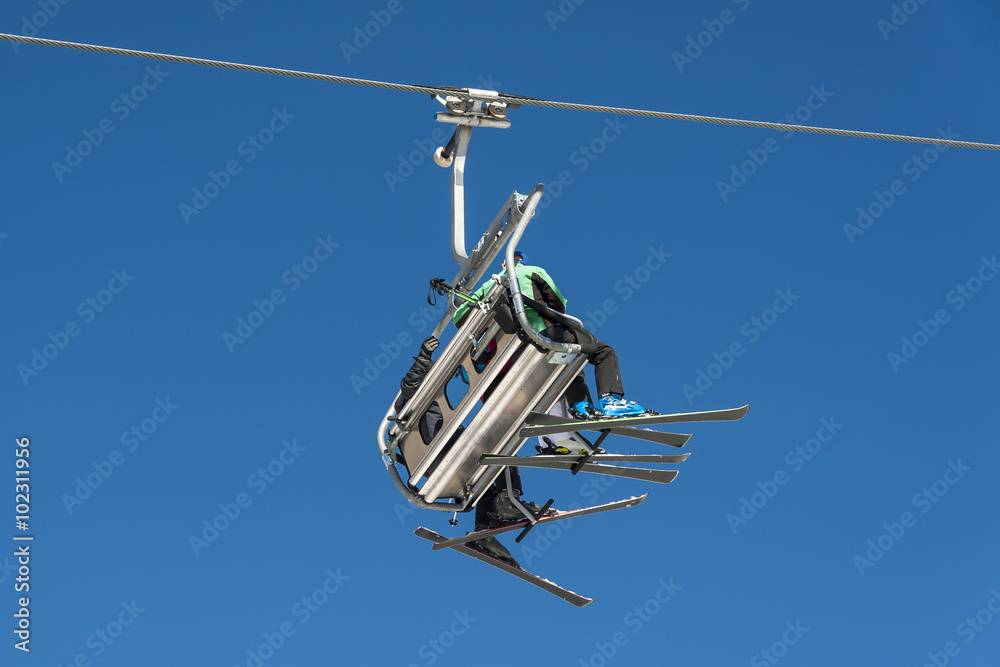 Skiers sitting on a chairlift at a ski resort.