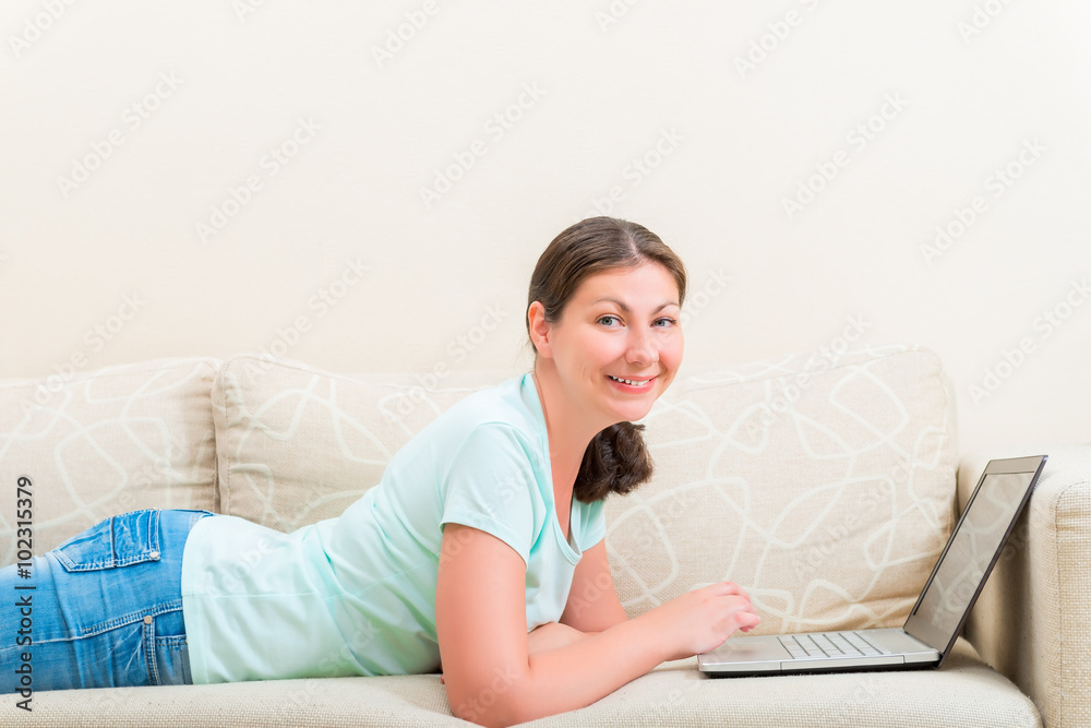 portrait of happy girl with a laptop lying on the sofa portrait of happy girl with a laptop lying on the sofa
