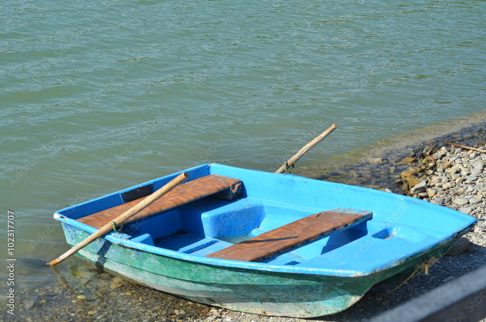 Old wooden boat for water walks on the pebbled shore of a mountain lake
