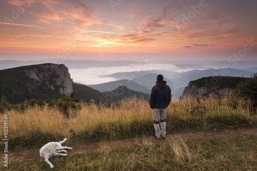 Man and his faithful friend the dog admire the mountain scenery
