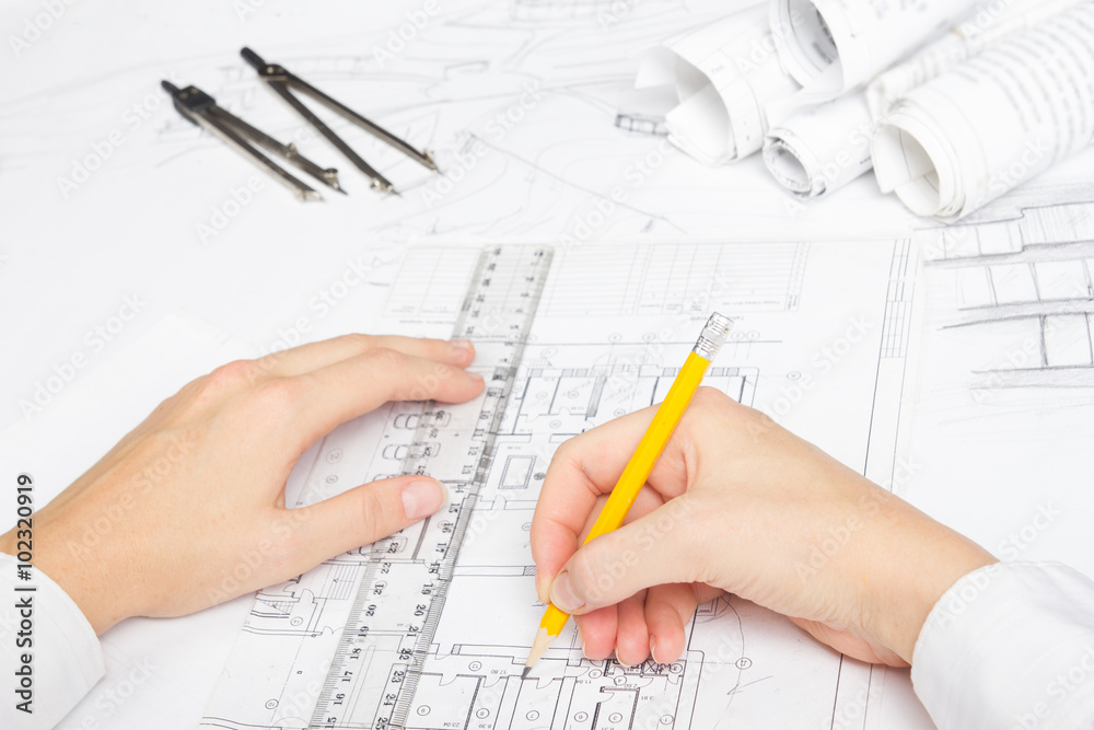Architect working on blueprint. Architects workplace - architectural project, blueprints, ruler, calculator, laptop and divider compass. Construction concept. Engineering tools Architect working on blueprint. Architects workplace - architectural project, blueprints, ruler, calculator, laptop and divider compass. Construction concept. Engineering tools