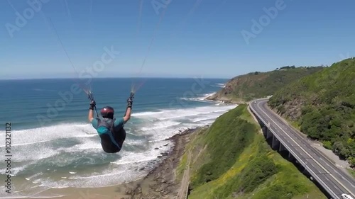 POV Paraglider Pilot Chase Cam following behind pilot flying next to a road by the beach in Wilderness, South Africa.