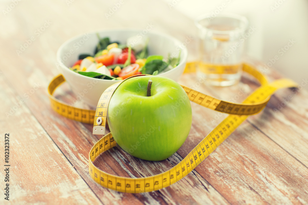 close up of green apple and measuring tape close up of green apple and measuring tape