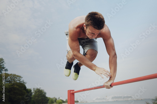 young man exercising on horizontal bar outdoors