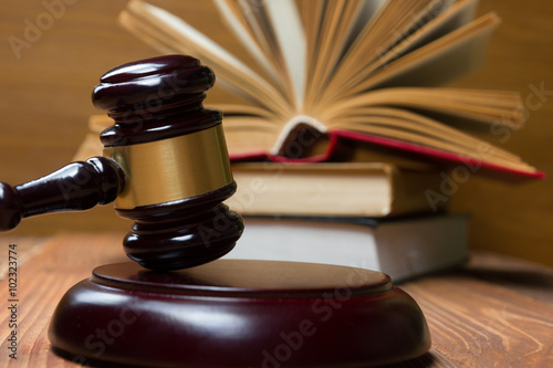 Law book with wooden judges gavel on table in a courtroom or law enforcement office.