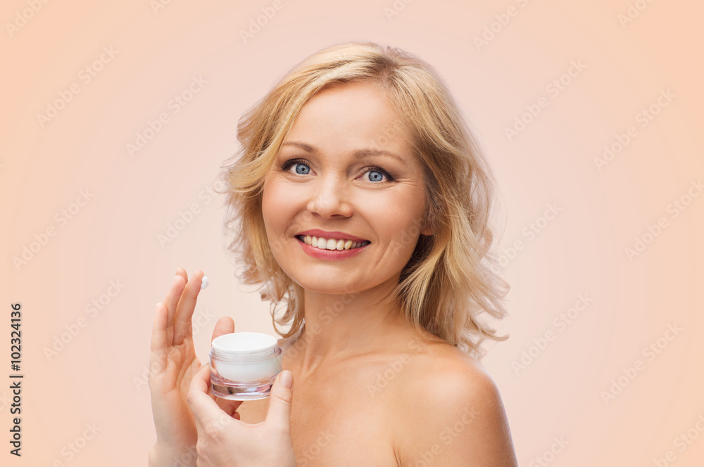 happy woman applying cream to her face happy woman applying cream to her face