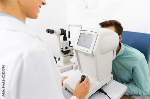 optician with autorefractor and patient at clinic photo
