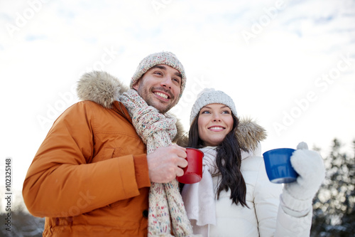 happy couple with tea cups over winter landscape