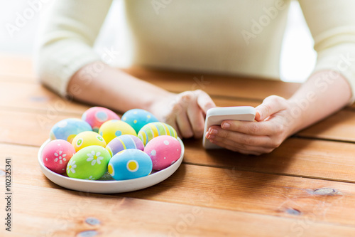 Canvas Print close up of hands with easter eggs and smartphone