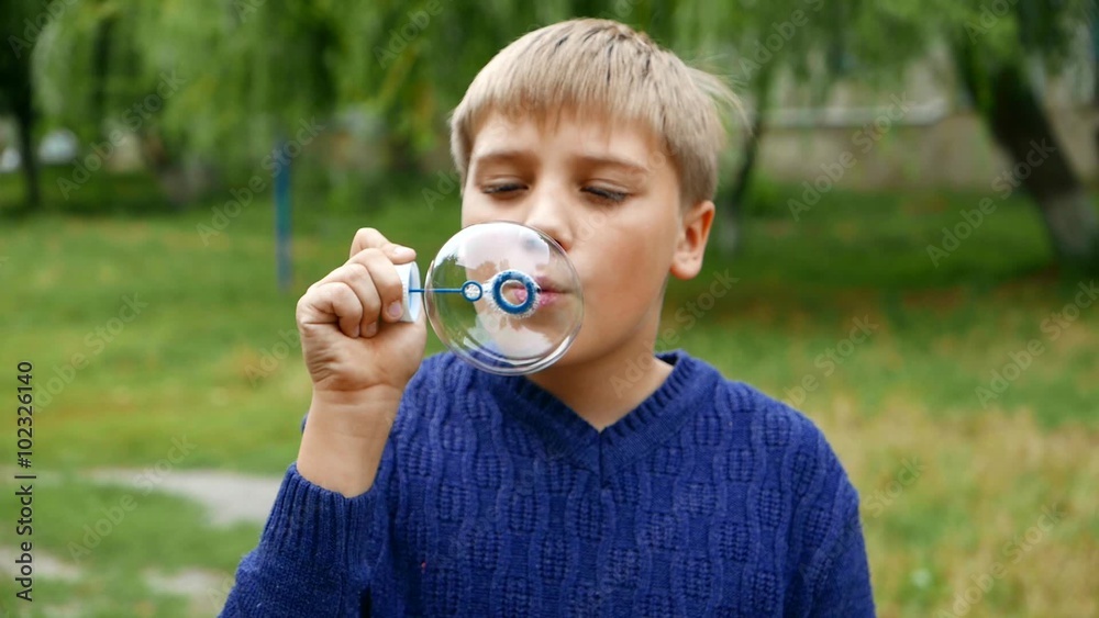 Happy child, caucasian teen boy blows soap bubbles on a background of beautiful summer green forest. Happy child, caucasian teen boy blows soap bubbles on a background of beautiful summer green forest.
