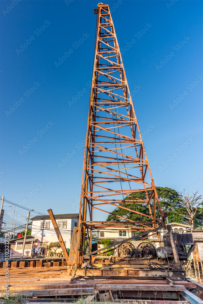 Traditional pile driver device with crane at construction site in Thailand. The machine is used to drive piles into soil to provide the foundation.